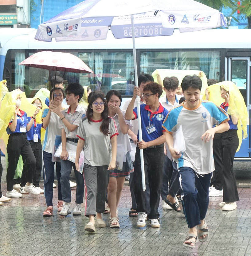 TP.HCM và nhiều nơi mưa to, thí sinh đi thi chú ý- Ảnh 4. Thí sinh được chiến sĩ tình nguyện che mưa vào điểm thi tại Trường THCS Nguyễn Gia Thiều, quận Tân Bình, TP.HCM - Ảnh: NHƯ HÙNG