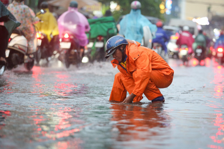 TP.HCM mưa to, cây bật gốc, còn mưa đến tối toàn thành phố- Ảnh 6. Nhân viên thoát nước mở nắp cống để nước thoát tại đường Ung Văn Khiêm, quận Bình Thạnh - Ảnh: PHƯƠNG QUYÊN